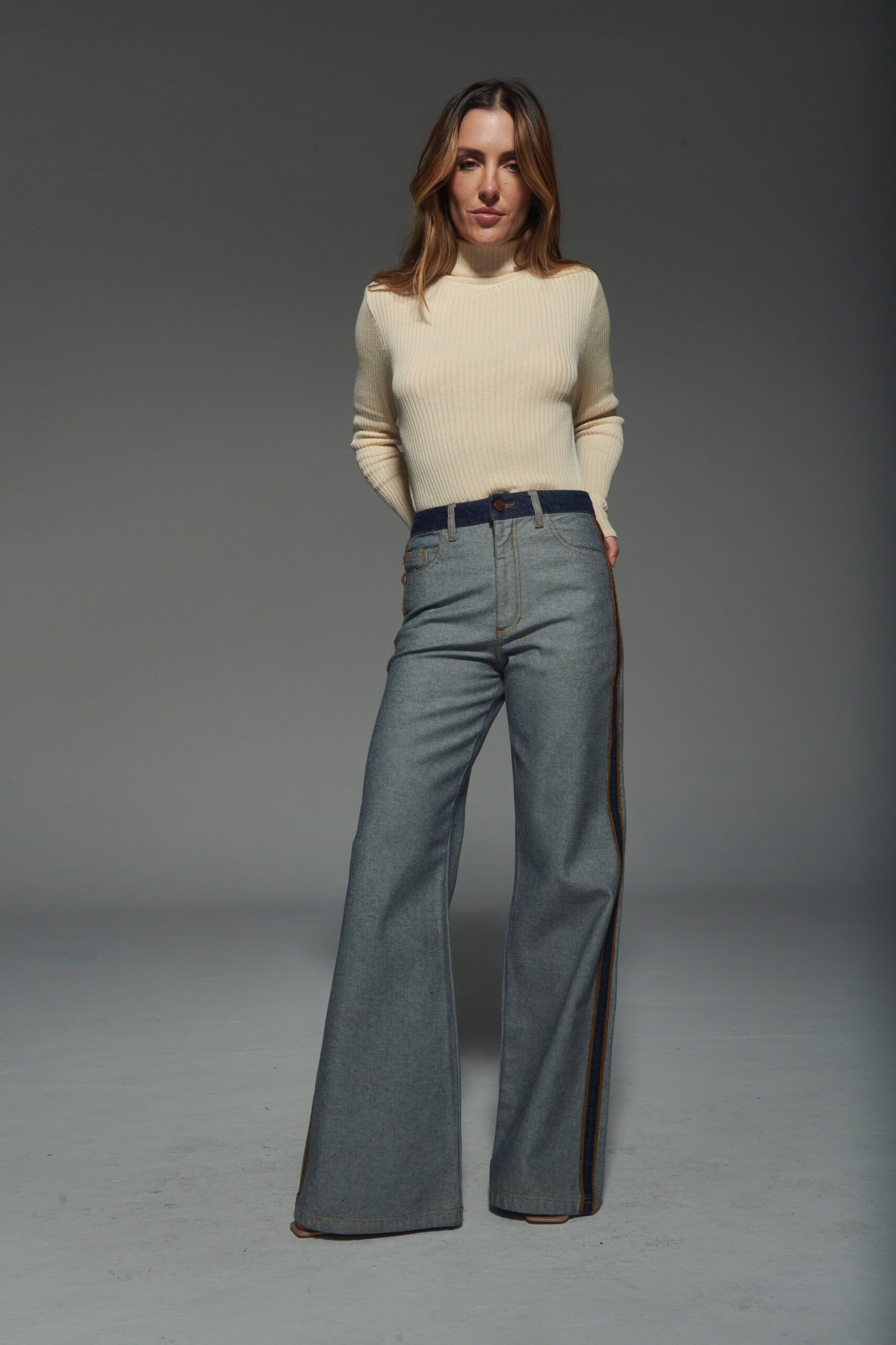 Calça jeans flare azul acinzentada, 100% algodão, com lado avesso do tecido, sem bolsos aparentes e passantes para cinto